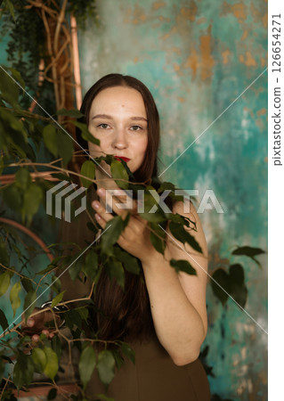 A woman with long hair holds vibrant leaves in a beautiful, calming, naturefilled setting 126654271