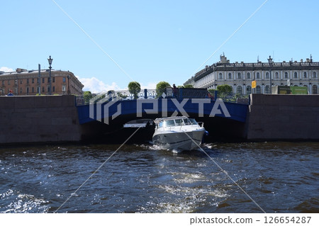 A boat gracefully passing under a bridge in a scenic waterfront city, ideal for adventure 126654287