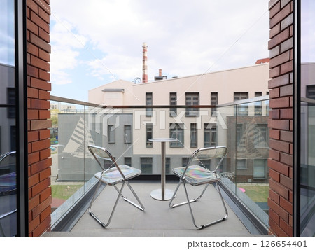 A modern balcony equipped with comfortable chairs, offering a stunning view of the urban scenery A modern balcony equipped with comfortable chairs, offering a stunning view of the urban scenery 126654401
