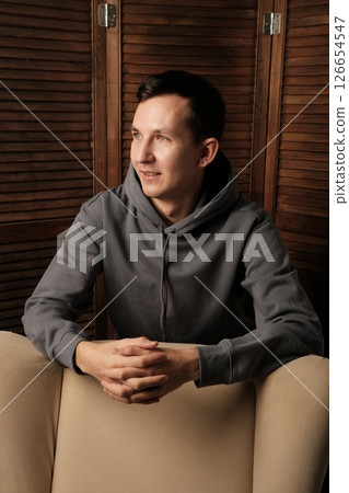 A Thoughtful Young Man Dressed in Casual Attire is Relaxing Comfortably in a Modern Setting 126654547