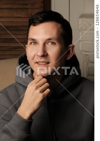 A curious and contemplative young man dressed in casual attire, surrounded by a cozy atmosphere 126654648