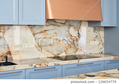 Stylish and Modern Kitchen Featuring a Marble Backsplash and Beautiful Blue Cabinets 126654779
