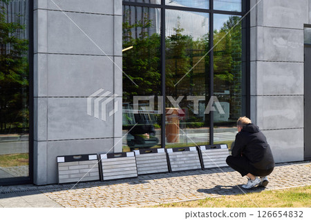 A person observes an eyecatching display near a building showcasing modern architecture 126654832