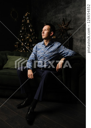 A Thoughtful and Contemplative Man Wearing a Stylish Outfit is Sitting Comfortably on a Sofa 126654852