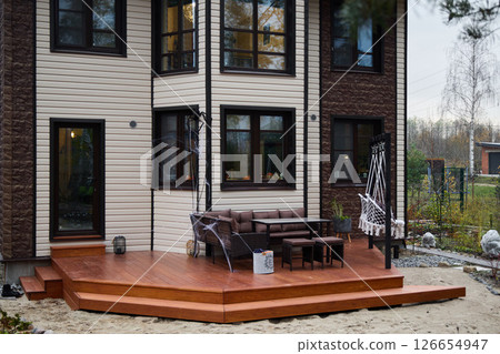 Discover a Stylish Outdoor Deck featuring Modern Furniture Set next to a Contemporary Home 126654947