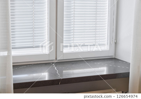 An Elegant Window Sill adorned with Modern Blinds that invite Natural Light into the room 126654974