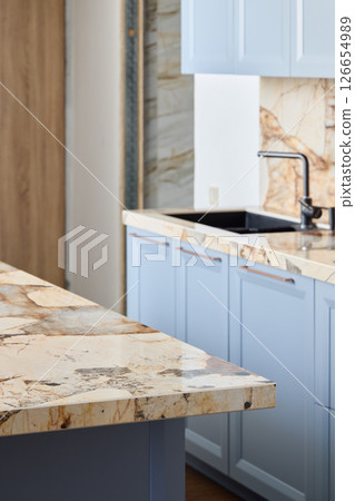 An Elegant Kitchen Design Featuring Beautiful Marble Countertops and Light Blue Cabinets 126654989