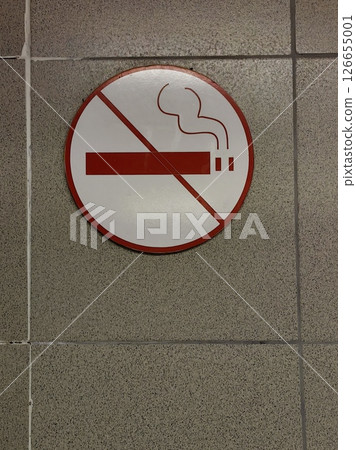 no smoking sign displayed on tiled wall in public building during daylight hours. closeup. 126655001