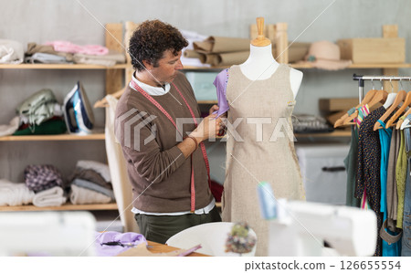 Man tailor adjusts clothes on mannequin Man tailor adjusts clothes on mannequin 126655554