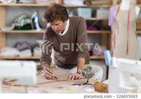 Man dressmaker drawing pattern on paper in workshop Man dressmaker drawing pattern on paper in workshop 126655683