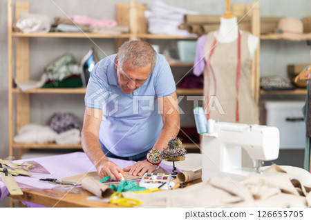 Man tailor marks fabric in sewing workshop Man tailor marks fabric in sewing workshop 126655705