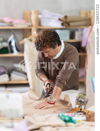 Man tailor cuts paper dress pattern and work with hand snip 126655725