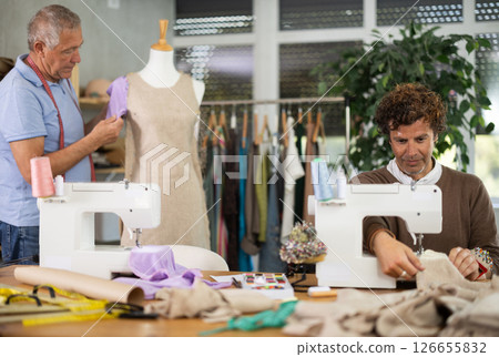 Adult man sews on machine male assistant sews on mannequin 126655832