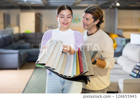 Cheerful couple deciding on material for couch in furniture store 126655943