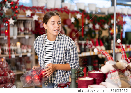 Girl buyer dreams of merry Christmas holiday and buys souvenirs to relatives and friends. 126655982