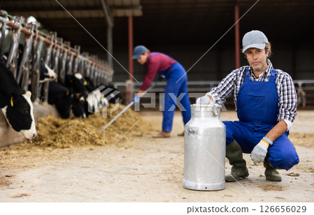 Adult male farmer with can works on dairy farm Adult male farmer with can works on dairy farm 126656029