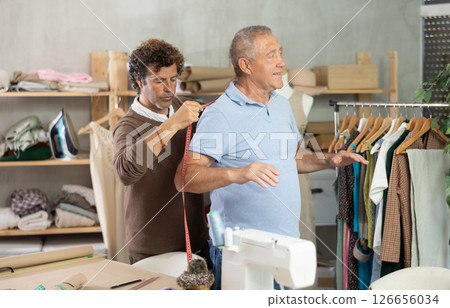 Man tailor takes measurements from senior male client Man tailor takes measurements from senior male client 126656034