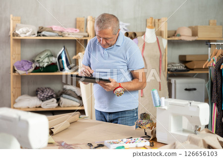 Man tailor makes pattern using tablet Man tailor makes pattern using tablet 126656103