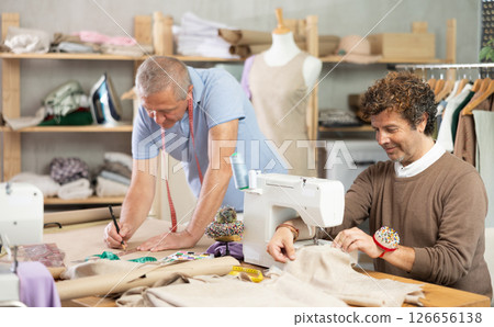 Mature tailor cutting paper next to male tailor Mature tailor cutting paper next to male tailor 126656138
