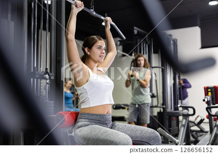 Woman is engaged in a simulator for development of back muscles 126656152