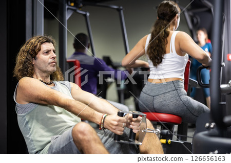 Caucasian man is engaged in a simulator with horizontal weights in gym 126656163