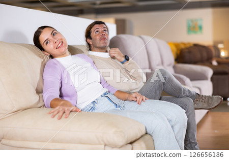 Cheerful couple trying out sofa in furniture showroom Cheerful couple trying out sofa in furniture showroom 126656186