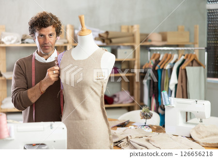 Man tailor connects parts of dress on mannequin Man tailor connects parts of dress on mannequin 126656218