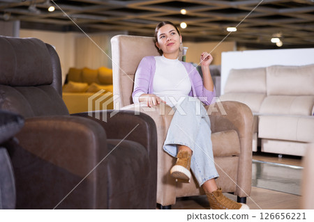 Woman trying out armchair in furniture showroom 126656221