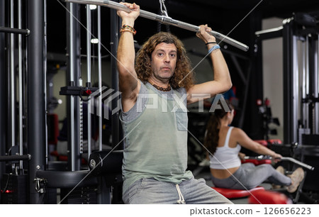 Caucasian man is engaged in a simulator for development of back muscles 126656223