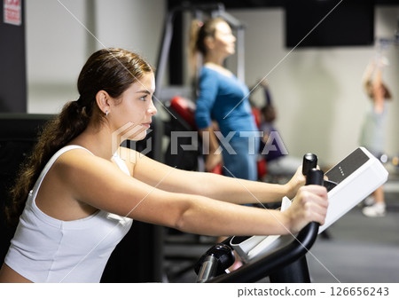 Caucasian woman using exercise bicycle in gym 126656243
