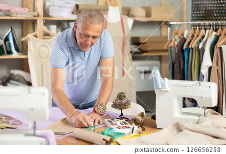 Senior man tailor draw dress pattern of product on paper Senior man tailor draw dress pattern of product on paper 126656258