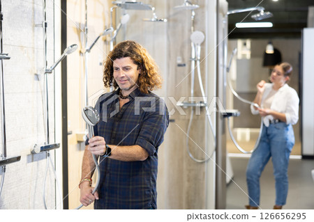 Man looking to buy new shower fixture for bathroom in store Man looking to buy new shower fixture for bathroom in store 126656295