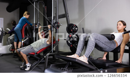 Men and women training on machines in gym 126656334