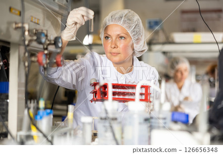 Female lab technician working with reagents in test tubes during chemical experiment 126656348