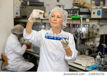 Female pharmacist researcher waiting for color change in test tube while conducting experiment in laboratory Female pharmacist researcher waiting for color change in test tube while conducting experiment in laboratory 126656350