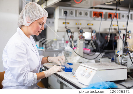 Skilled middle-aged female biochemist examining solution in test tube for chemical reaction in research center Skilled middle-aged female biochemist examining solution in test tube for chemical reaction in research center 126656371