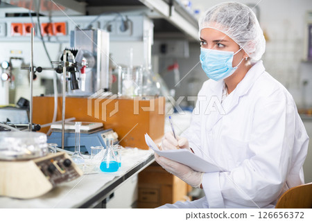 Scientist engaged in research in chemical laboratory, noting results in test chart Scientist engaged in research in chemical laboratory, noting results in test chart 126656372