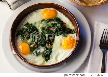 Fried eggs with spinach, raisins and ham, dish of Catalan cuisine 126656378