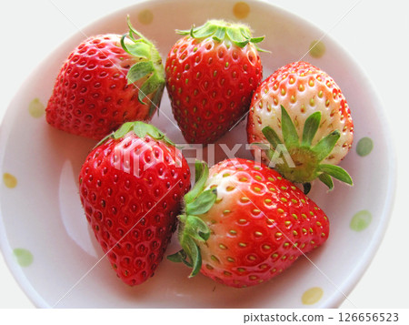 Five strawberries with stems on a white plate 126656523