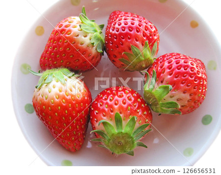 Five strawberries with stems on a white plate 126656531