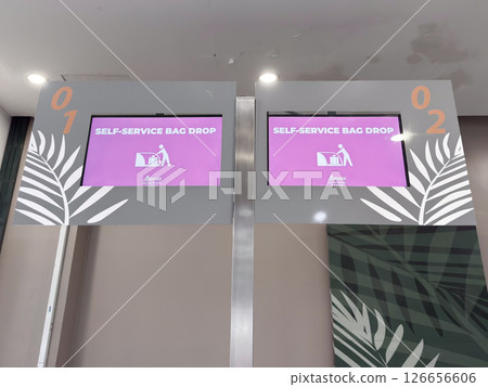 Self-service bag drop kiosks at airport with digital screens displaying instructions Self-service bag drop kiosks at airport with digital screens displaying instructions 126656606