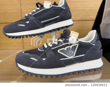 Stylish black and white Emporia Armani sneakers displayed on a glass shelf in a modern retail store 126656612