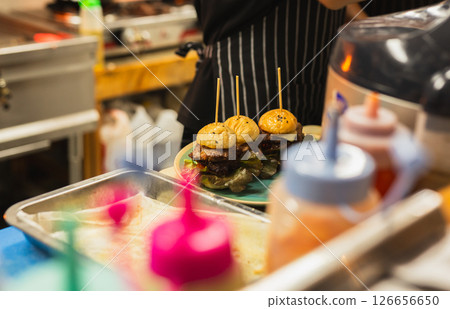 Hamburger being prepared in the kitchen with green salad. 126656650