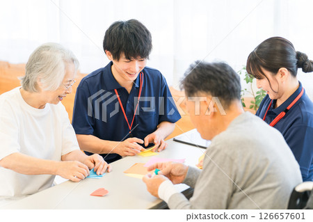 集體住宅或養老院中的老年人和男性和女性護理人員正在摺紙 126657601