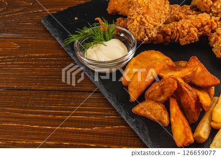 Crispy fried chicken served with golden potato wedges and dip Crispy fried chicken served with golden potato wedges and dip 126659077