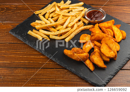 Various types of fried potatoes served on a black slate board 126659092