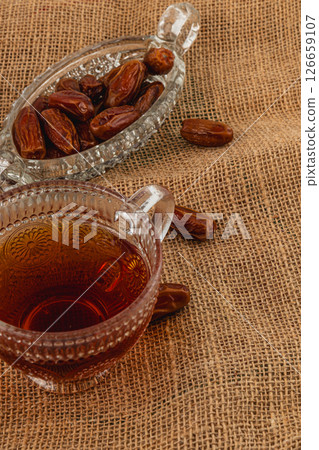 Warm tea served with sweet dates on burlap tablecloth Warm tea served with sweet dates on burlap tablecloth 126659107