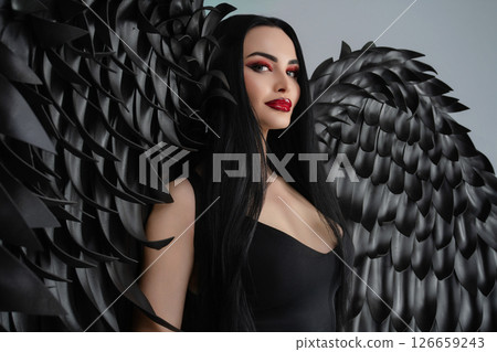 Elegant woman in lingerie poses with striking black wings for a dramatic look Elegant woman in lingerie poses with striking black wings for a dramatic look 126659243