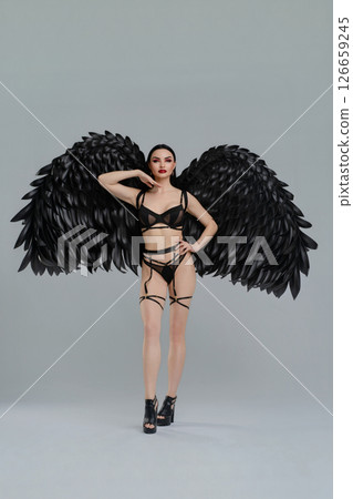 Lingerie model showcases black wings in a bold fashion display 126659245