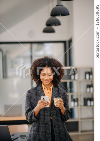 Confident business expert attractive smiling young woman typing laptop ang holding digital tablet  on desk in office. 126659695
